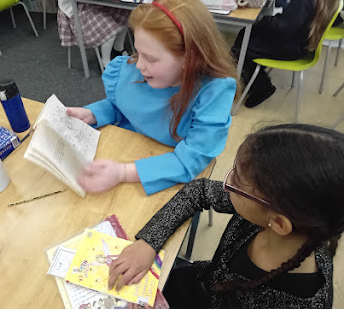 two children sat reading at a table