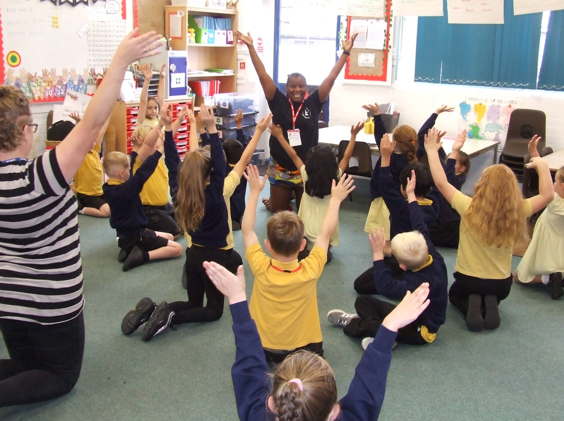 Children kneeling with arms raised in a classroom
